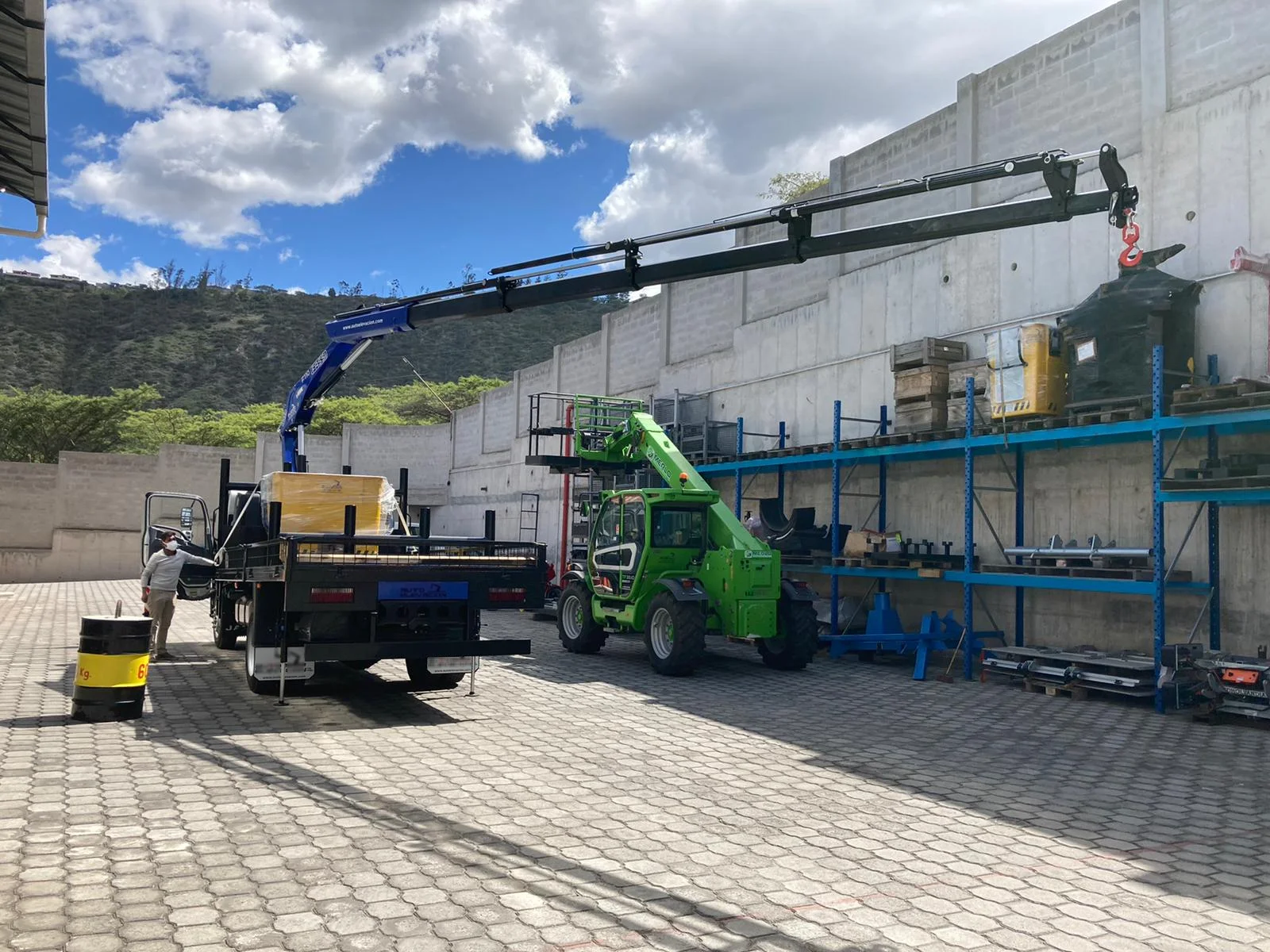 Camión grúa de DILEXSA cargando equipo industrial en bodega — capacidad de izaje y maniobra de carga pesada